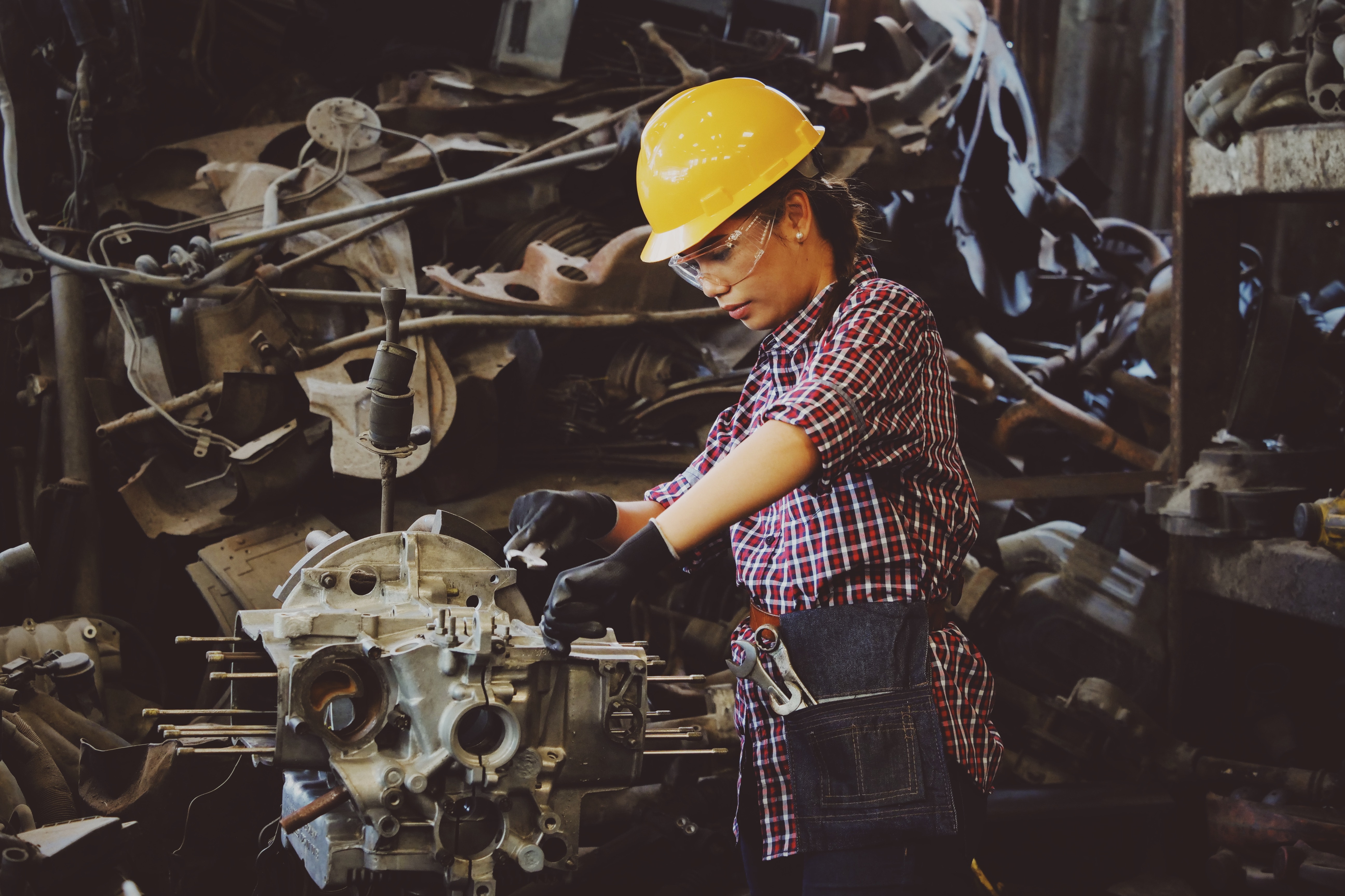 Assembly work at a factory in Ukraine. A woman is working, in gloves and a yellow hard hat.