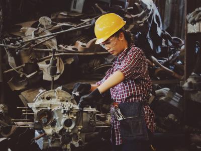 Assembly work at a factory in Ukraine. A woman is working, in gloves and a yellow hard hat.